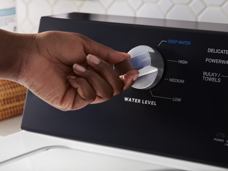 A person selecting a cycle on a washing machine A person selecting a cycle on a washing machine