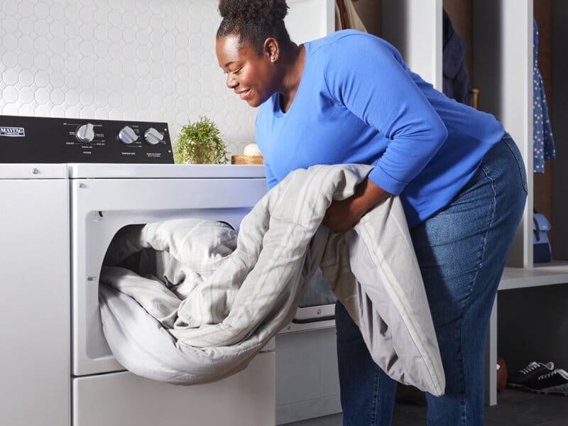 A person pulling clothes out of a washer A person pulling clothes out of a washer