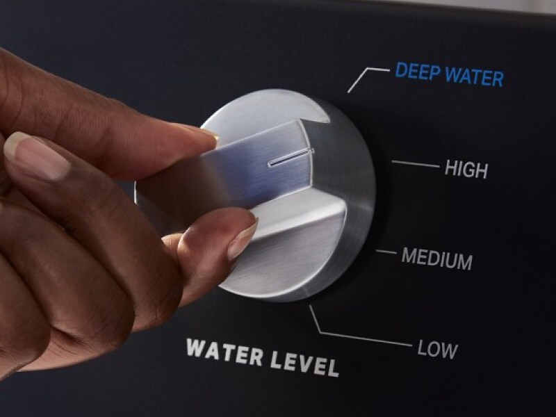 Close-up of a person selecting a cycle on a Maytag brand washer