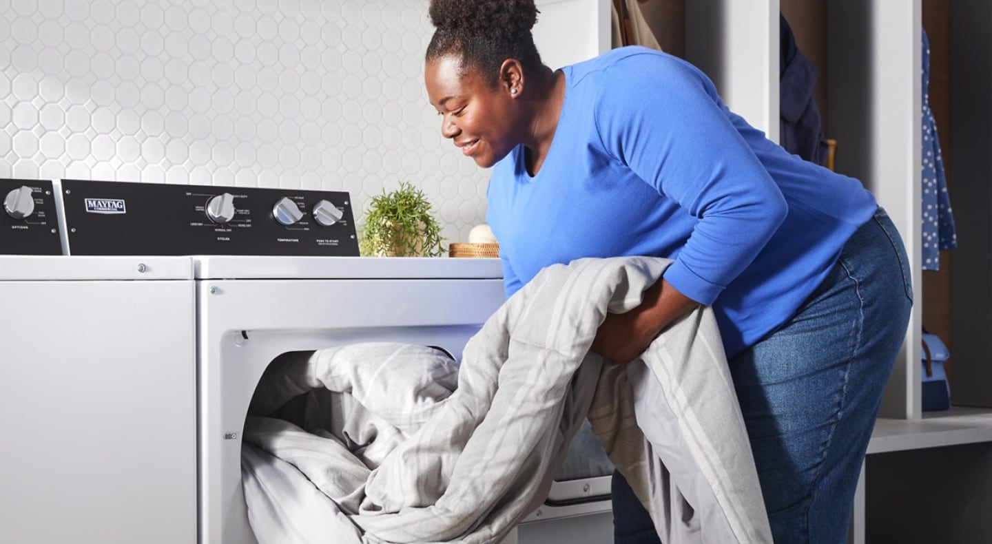 Person unloading comforter from commercial-grade dryer Person unloading comforter from commercial-grade dryer