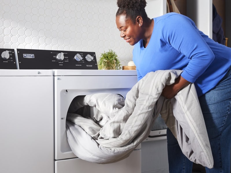 Person unloading comforter from commercial-grade dryer Person unloading comforter from commercial-grade dryer