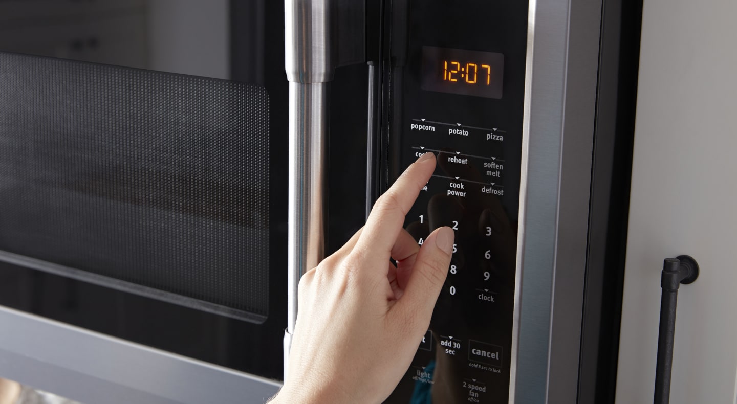 Person selecting settings on a microwave control panel Person selecting settings on a microwave control panel