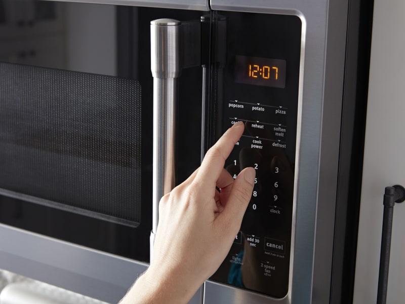 Person selecting settings on a microwave control panel Person selecting settings on a microwave control panel