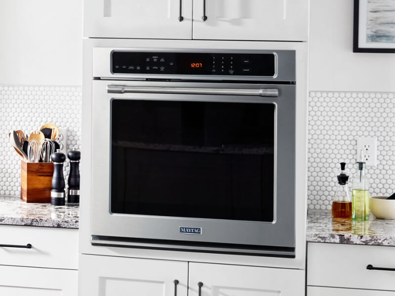 A Maytag® wall oven surrounded by white cabinetry