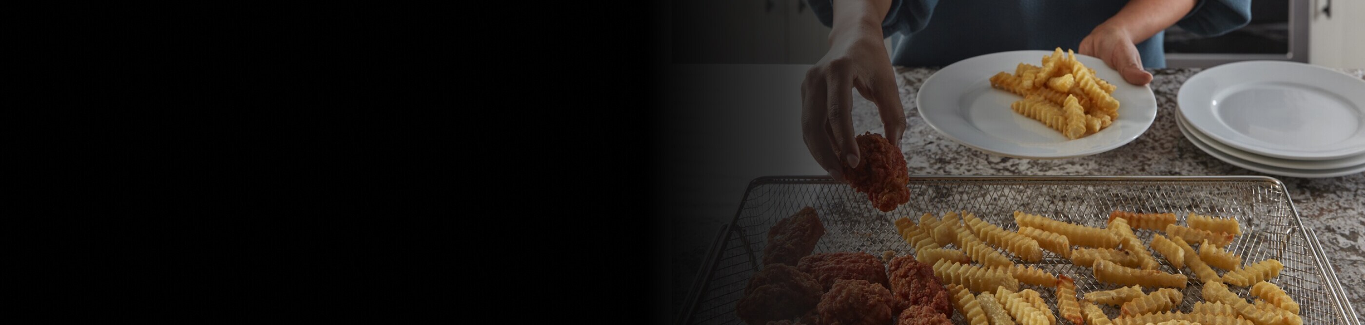 Person transferring chicken and fries from air fry basket to plate