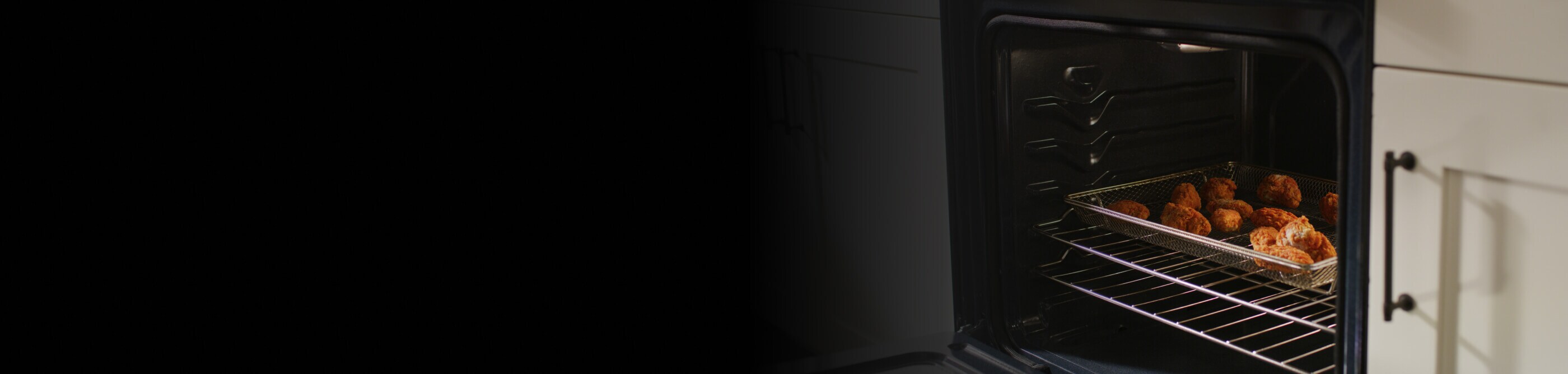 Open oven with food cooking inside of an air fry basket