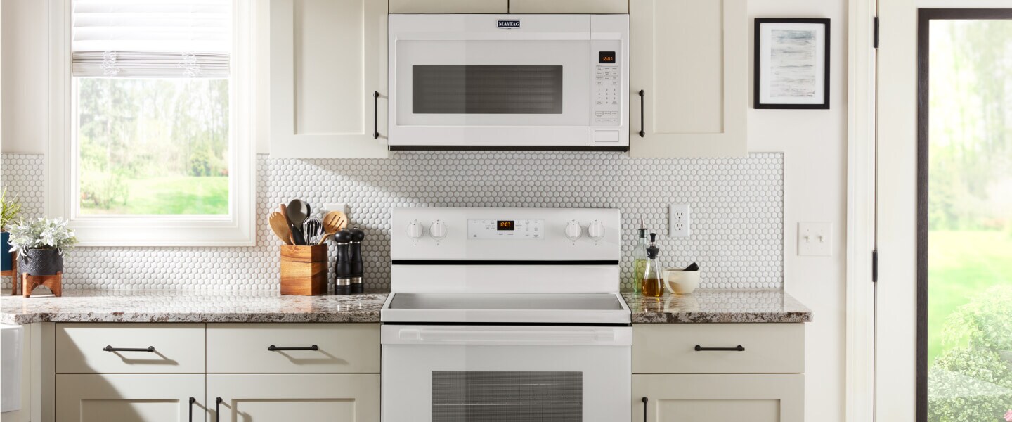Front view of white kitchen with white Maytag® range and microwave