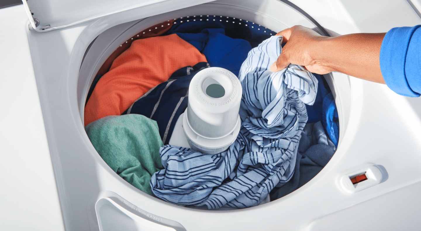 Person putting clothing in a washer Person putting clothing in a washer