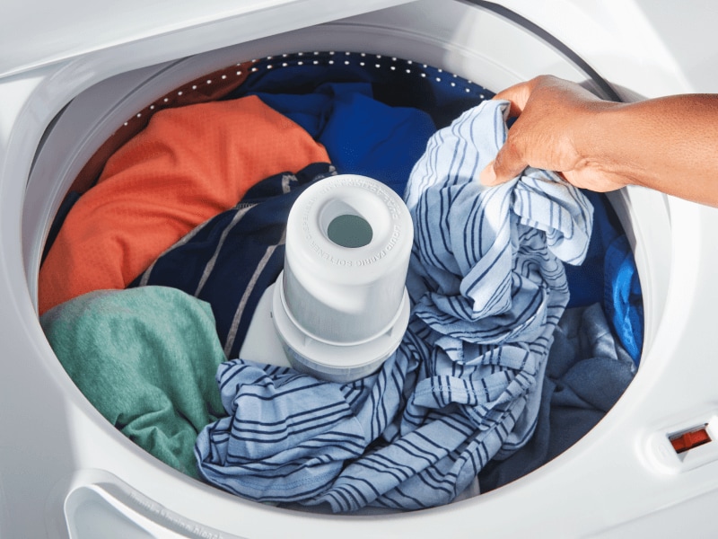 Person putting clothing in a washer Person putting clothing in a washer
