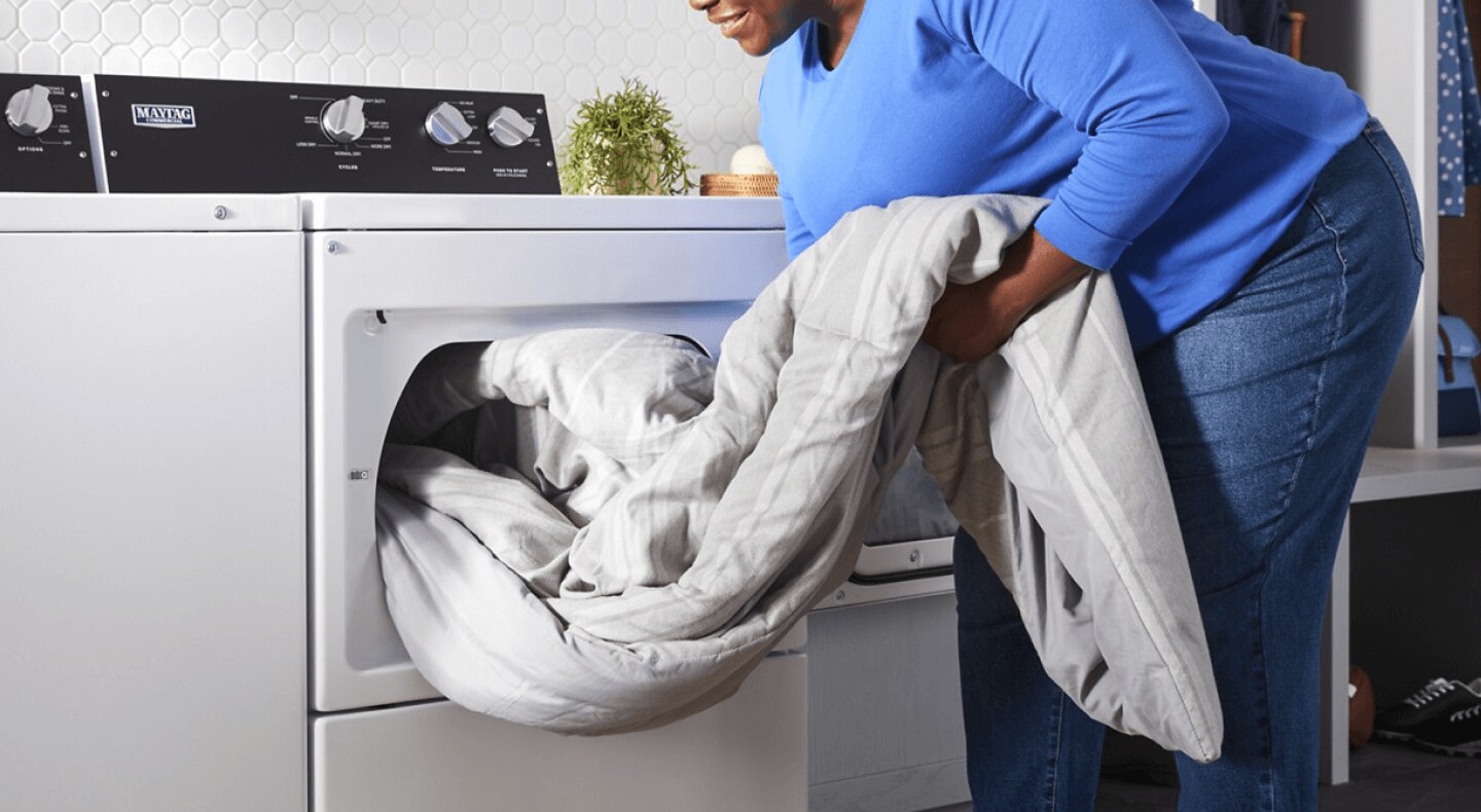 Person removing a comforter from a dryer Person removing a comforter from a dryer