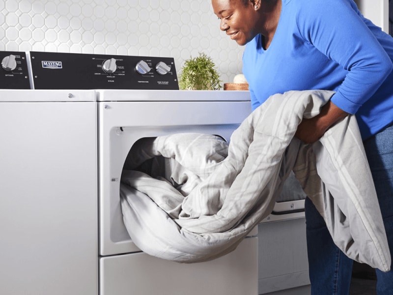 Person removing a comforter from a dryer Person removing a comforter from a dryer