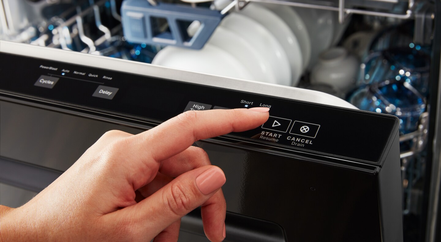A person pressing the start button on a dishwasher A person pressing the start button on a dishwasher