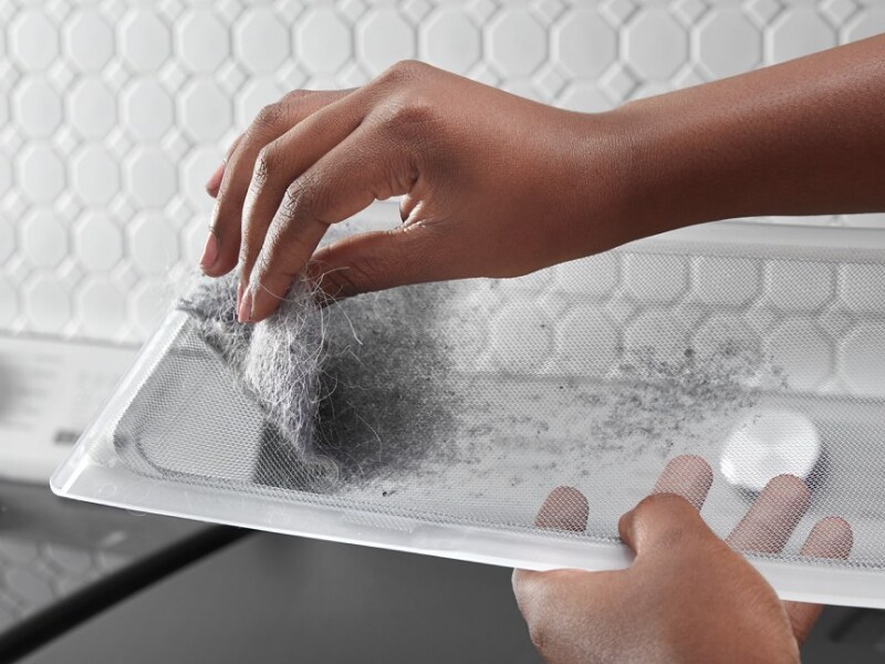 A person removing pet hair from a Maytag® dryer lint screen