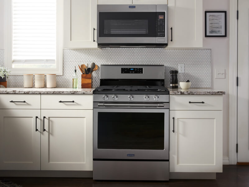 Maytag® stainless steel range between white cabinetry beneath over-the-range microwave Maytag® stainless steel range between white cabinetry beneath over-the-range microwave