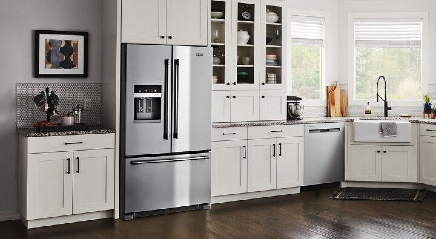 Stainless steel French door refrigerator from Maytag brand in kitchen with white cabinetry