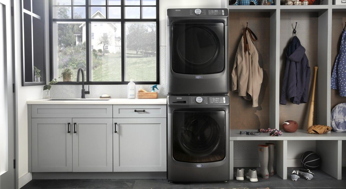 Stacked Maytag® front load laundry pair next to shelving in laundry room