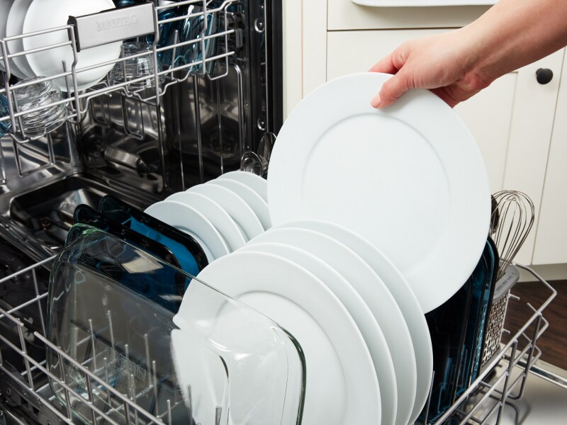 Person putting dishes in a dishwasher Person putting dishes in a dishwasher