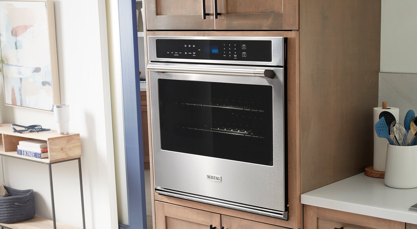 A Maytag® wall oven in a kitchen with brown cabinets
