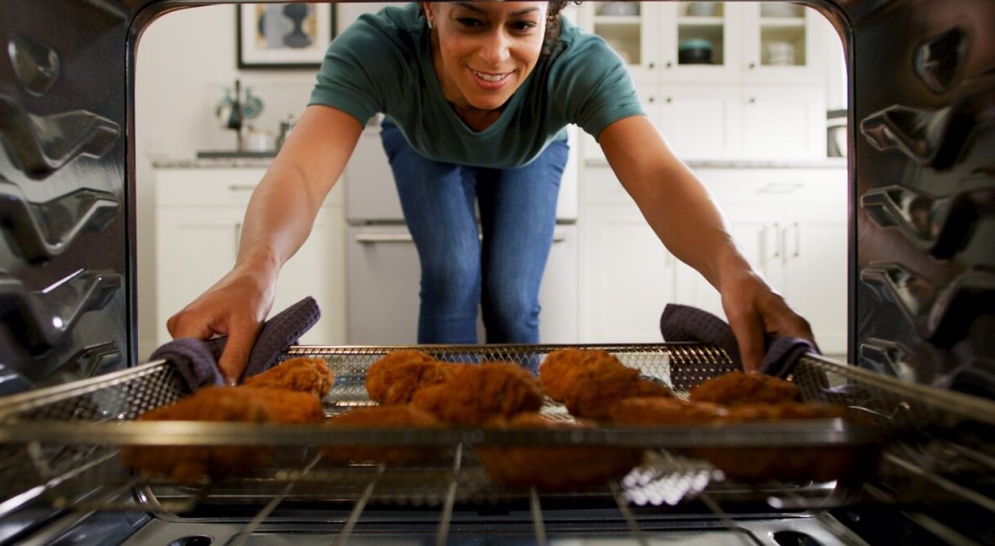 Person removing air fry basket with food in it from the oven  Person removing air fry basket with food in it from the oven