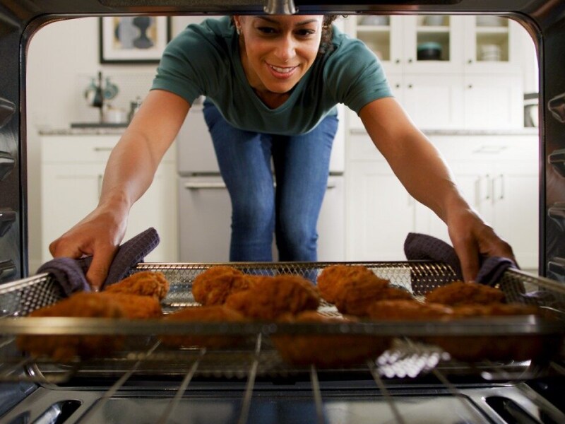 Person removing air fry basket with food in it from the oven  Person removing air fry basket with food in it from the oven