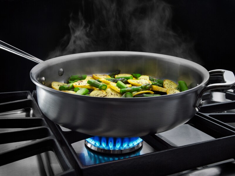 Vegetables cooking in a pan on a gas cooktop Vegetables cooking in a pan on a gas cooktop