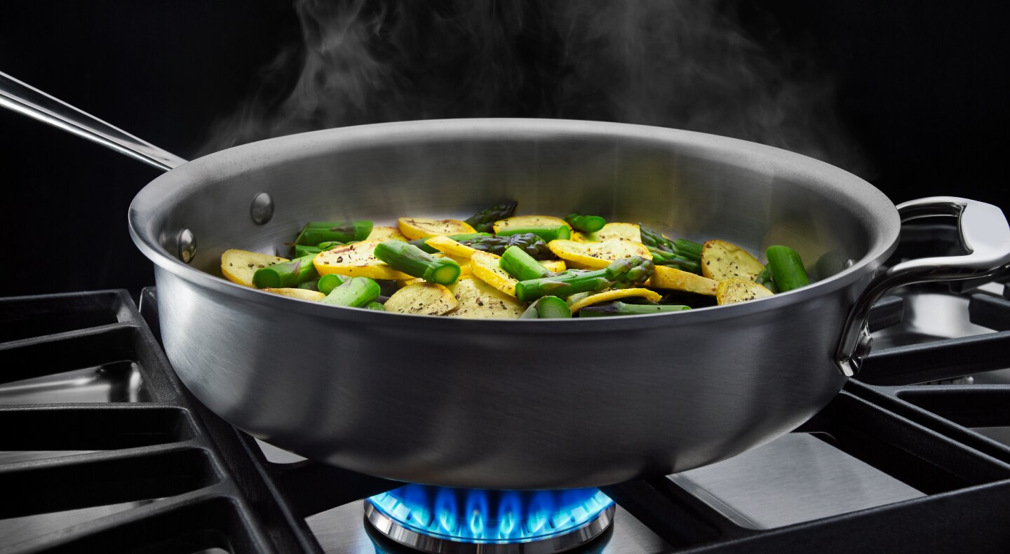 Vegetables cooking in a pan on a gas cooktop Vegetables cooking in a pan on a gas cooktop