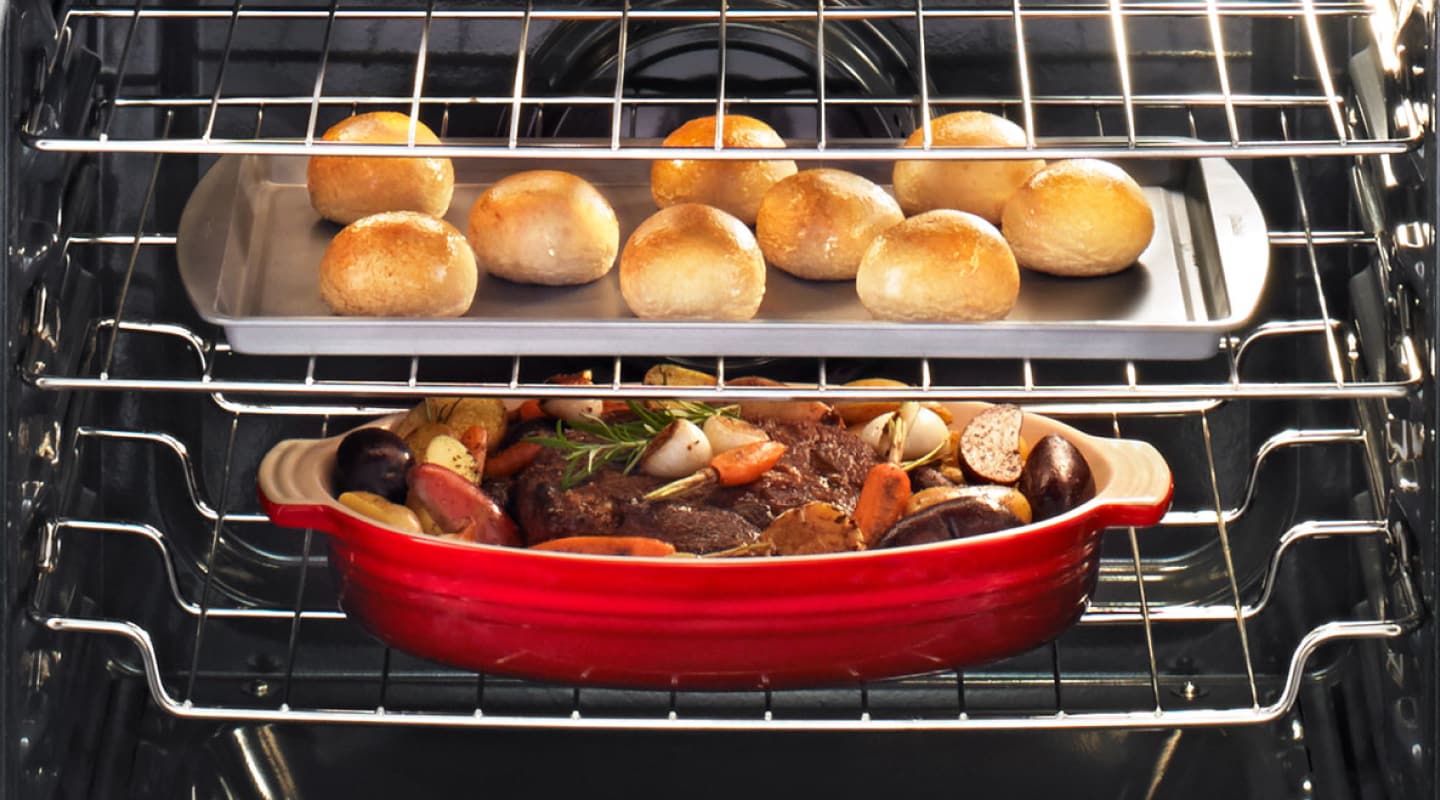 Meat with roasted vegetables cooking under a baking sheet with rolls Meat with roasted vegetables cooking under a baking sheet with rolls