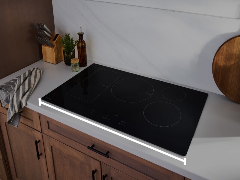 An induction cooktop with a line measuring the width of the surface