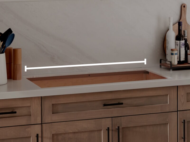 A cooktop cutout within countertops with a line measuring the width of the cutout