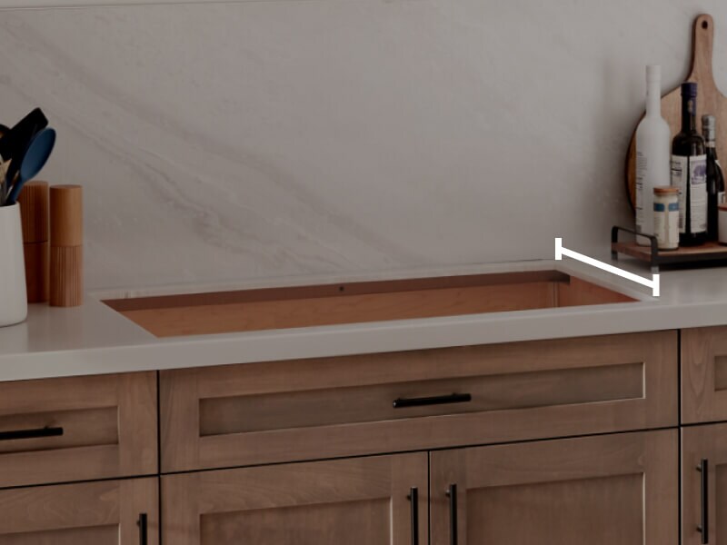 A cooktop cutout within countertops with a line measuring the depth of the cutout