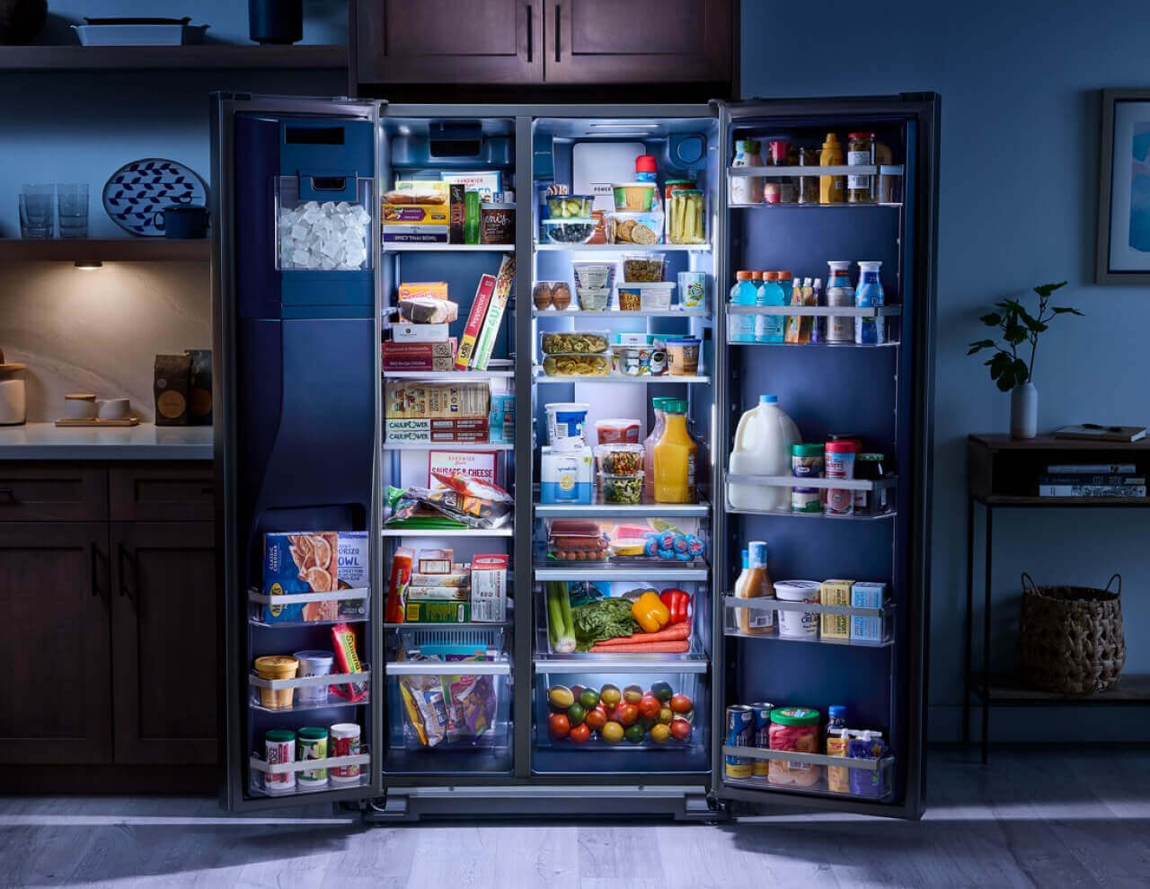 Open side-by-side refrigerator stocked with food and featuring a blue interior
