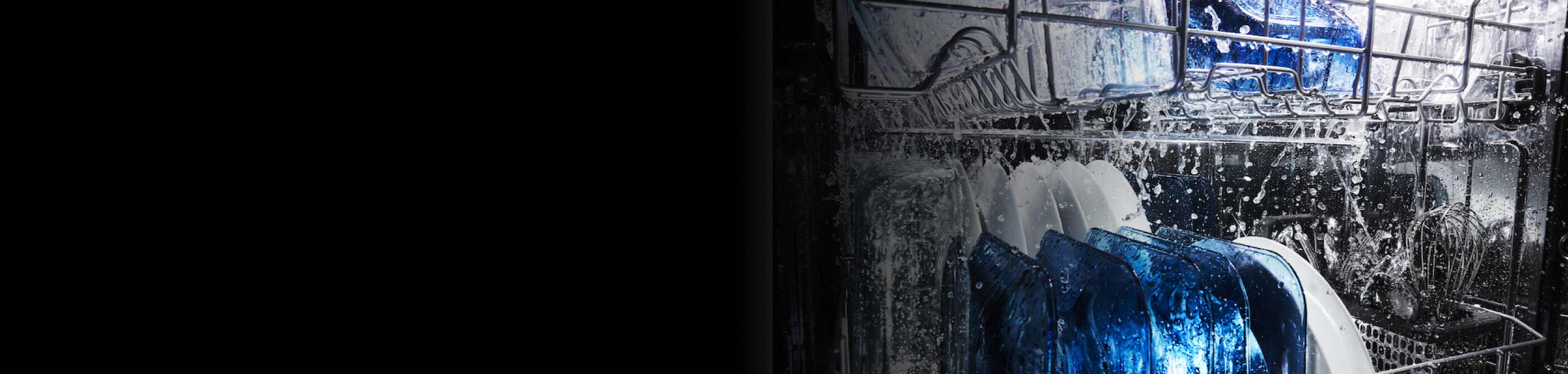 Blue and white dishes inside a dishwasher with water spraying on them