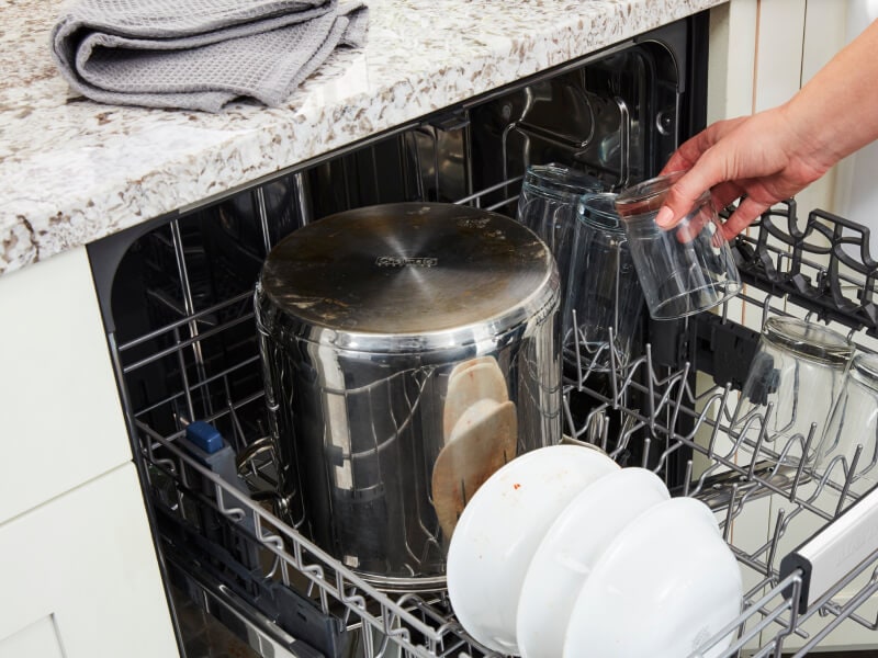 Person loading dishes on dishwasher racks