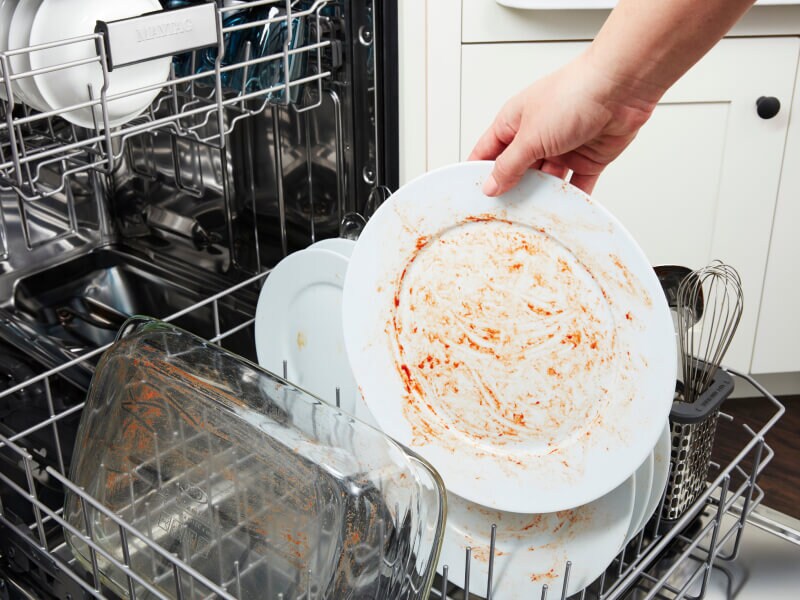Person placing dirty dishes in a dishwasher