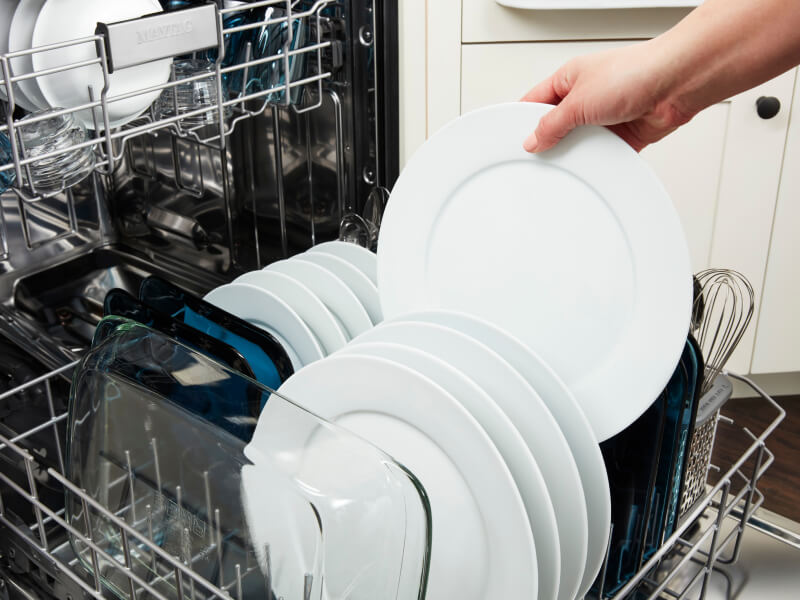 Person removing clean plate from a dishwasher