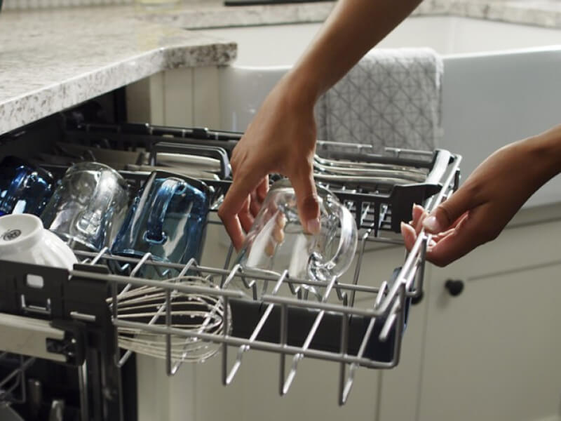 Person placing glass on dishwasher rack