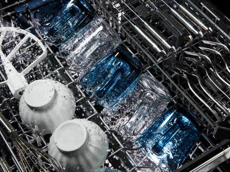 Dishes being washed inside a dishwasher Dishes being washed inside a dishwasher