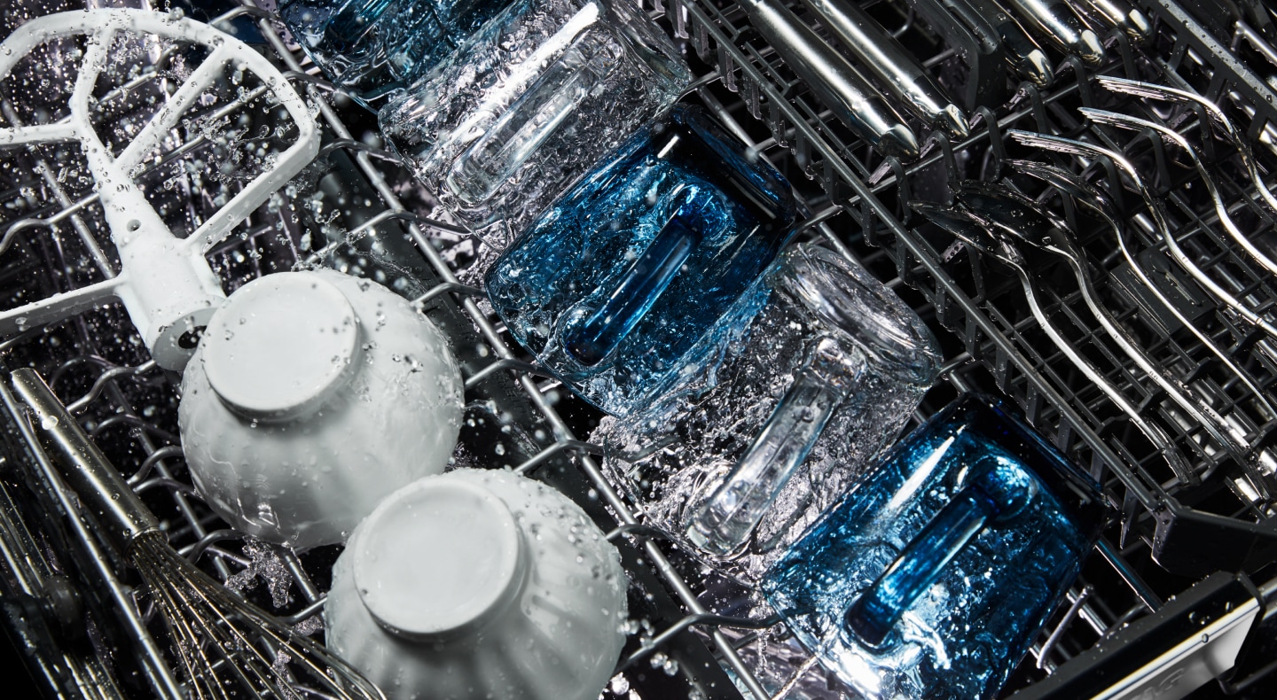 Dishes being washed inside a dishwasher Dishes being washed inside a dishwasher