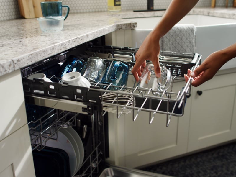 Person loading dishes into a dishwasher top rack Person loading dishes into a dishwasher top rack
