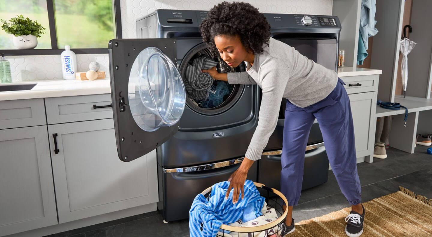 A person putting clothes in a washer