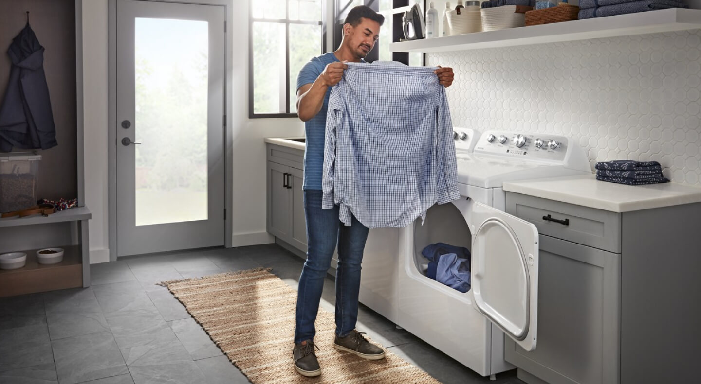 A person pulling a shirt out of a dryer
