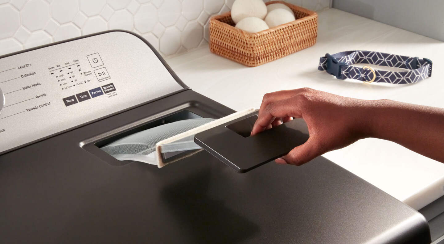 Person removing the lint trap from a Maytag® dryer Person removing the lint trap from a Maytag® dryer