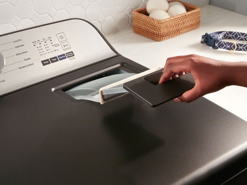 Person removing the lint trap from a Maytag® dryer Person removing the lint trap from a Maytag® dryer