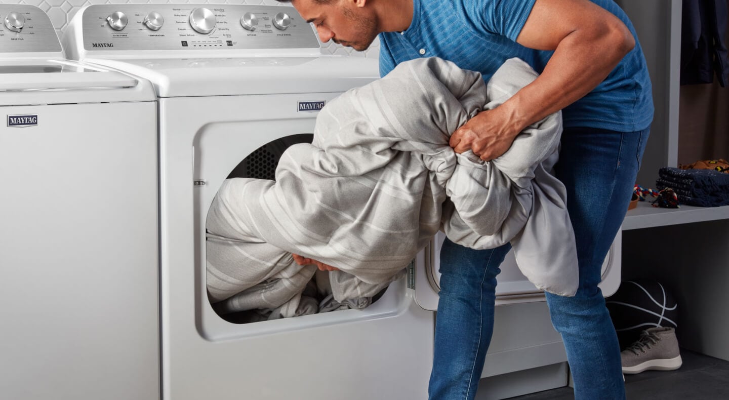 Person removing laundry from a Maytag® dryer Person removing laundry from a Maytag® dryer