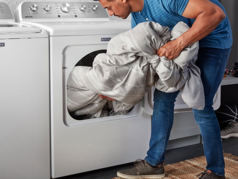Person removing laundry from a Maytag® dryer Person removing laundry from a Maytag® dryer