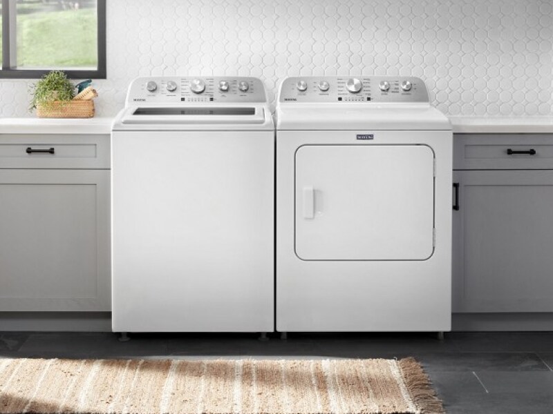 A white top load washer next to white front load dryer in kitchen entryway A white top load washer next to white front load dryer in kitchen entryway