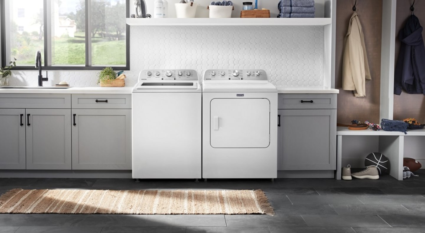 A white top load washer next to white front load dryer in kitchen entryway A white top load washer next to white front load dryer in kitchen entryway