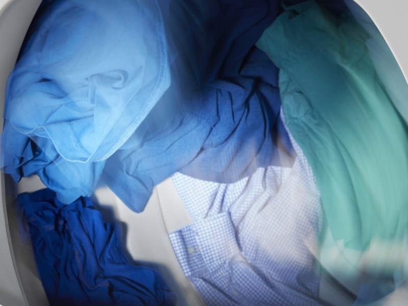 Blue and green colored clothes tumbling in dryer Blue and green colored clothes tumbling in dryer
