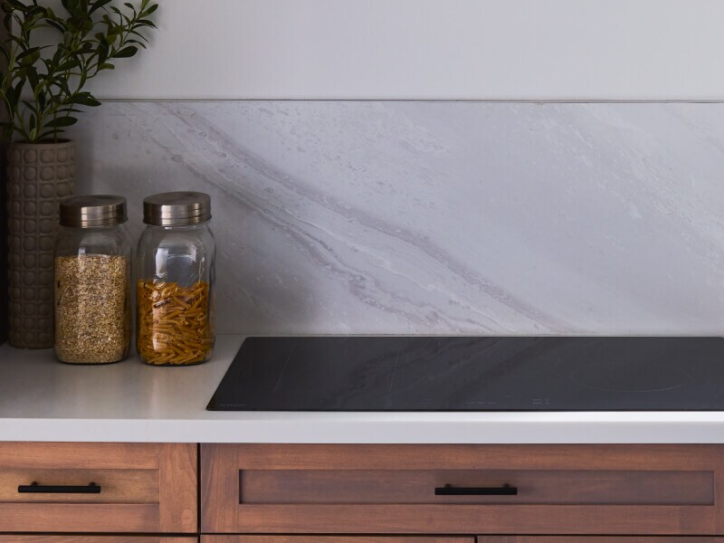 Maytag® induction cooktop in countertop next to jars of ingredients
