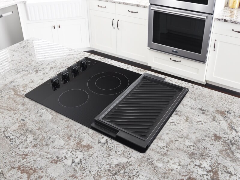 Maytag® electric cooktop with a reversible grill set in a granite counter top